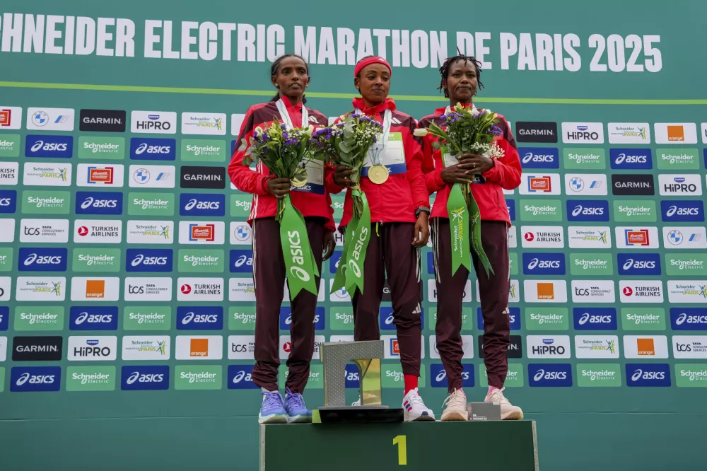 From left, second-placed Dera Dida of Ethiopia, winner Bedatu Hirpa of Ethiopia and third-placed Angela Tanui of Kenya pose on the podium of the Paris marathon, in Paris, Sunday, April 13, 2025. (AP Photo/Aurelien Morissard)