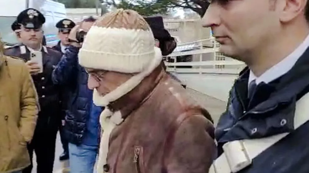In this picture taken from a video released by Italian Carabinieri on Monday, Jan. 16, 2023, top Mafia boss Matteo Messina Denaro, center, leaves an Italian Carabinieri barrack soon after his arrest at a private clinic in Palermo, Sicily, after 30 years on the run, Monday, Jan. 16, 2023. (Carabinieri via AP)