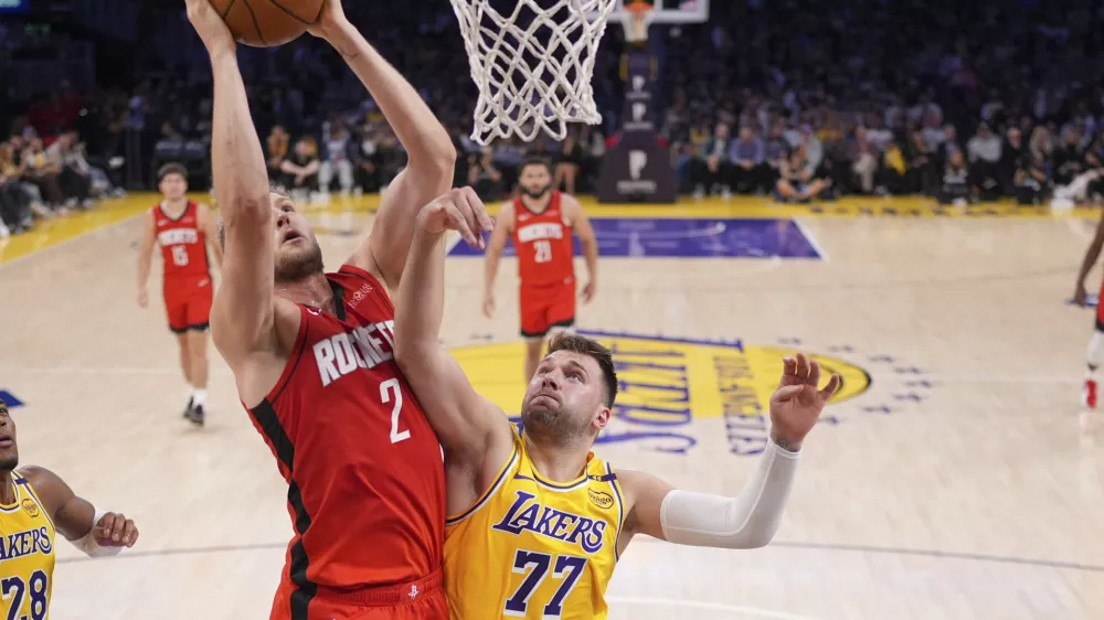 Houston Rockets center Jock Landale, left, shoots as Los Angeles Lakers guard Luka Doncic defends during the second half of an NBA basketball game Friday, April 11, 2025, in Los Angeles. (AP Photo/Mark J. Terrill)