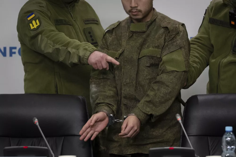 Ukrainian security officers escort a handcuffed Chinese national, center, who was captured by Ukrainian forces while fighting on the Russian side, to a press conference in Kyiv, Ukraine, Monday, April 14, 2025. (AP Photo/Efrem Lukatsky)