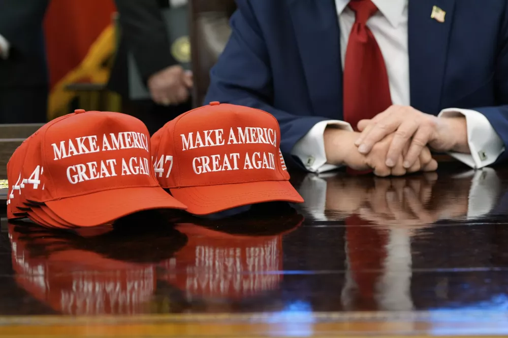 Hats are seen on the desk as President Donald Trump speaks with reporters after signing executive orders in the Oval Office of the White House, Wednesday, April 23, 2025, in Washington. (AP Photo/Alex Brandon) / Foto: Alex Brandon