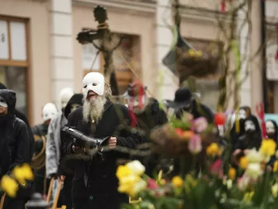 Participants dressed in black, wearing masks, beating drums and pushing small carts that make a synchronized and loud sound take part in an Easter procession through the streets of Ceske Budejovice, in Czech Republic, Friday, April 18, 2025. (AP Photo/Petr David Josek)