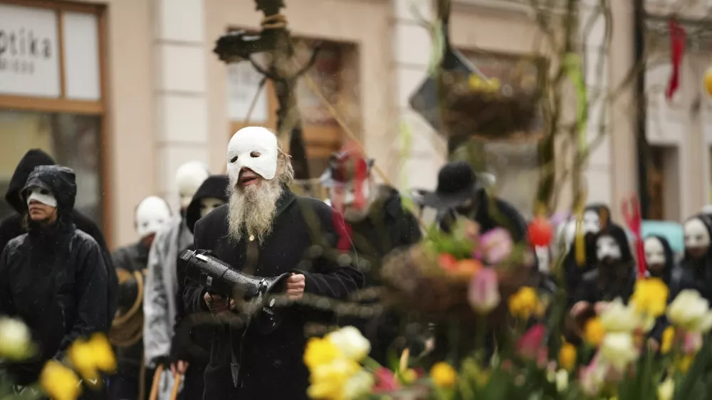 Participants dressed in black, wearing masks, beating drums and pushing small carts that make a synchronized and loud sound take part in an Easter procession through the streets of Ceske Budejovice, in Czech Republic, Friday, April 18, 2025. (AP Photo/Petr David Josek)