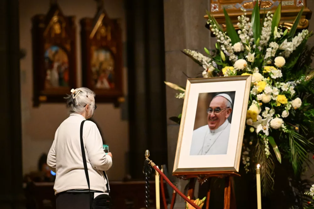 22 April 2025, Australia, Melbourne: A woman looks at a picture of Pope Francis at St Patrick's Cathedral following his death. The Argentine pontiff, who led the Catholic Church since 2013, passed away on Easter Monday at the age of 88, leaving a profound impact on millions around the world. Photo: James Ross/AAP/dpa