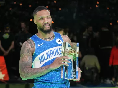 Milwaukee Bucks' Damian Lillard holds the trophy after winning the 3-point contest at the NBA basketball All-Star weekend, Saturday, Feb. 17, 2024, in Indianapolis. (AP Photo/Darron Cummings)