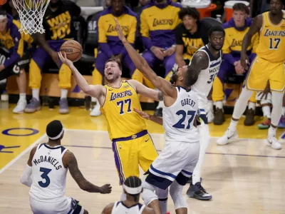 Los Angeles Lakers guard Luka Doncic (77) goes to the basket against Minnesota Timberwolves center Rudy Gobert (27) and forward Jaden McDaniels (3) during the second half of Game 2 of an NBA basketball first-round playoff in Los Angeles, Tuesday, April 22, 2025. (AP Photo/Eric Thayer)