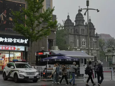 A mobile police station and a police car is parked near the Wangfujing Catholic Church also known as East Church in Beijing, Monday, April 21, 2025. (AP Photo/Ng Han Guan)