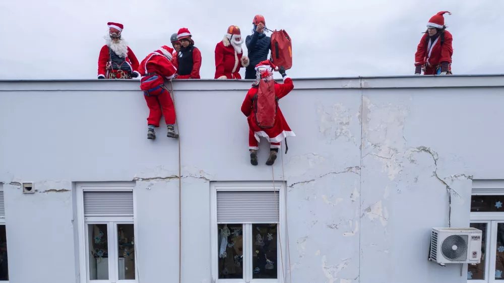 A drone view shows volunteers, dressed in Santa Claus costumes, rappelling from the roof of Children's Hospital Srebrnjak to bring gifts to the children, in Zagreb, Croatia December 23, 2024. REUTERS/Antonio Bronic