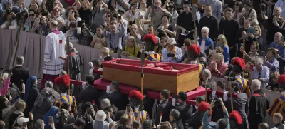 The body of Pope Francis is carried through St. Peter's Square to St. Peter's Basilica at the Vatican, Wednesday, April 23, 2025, where he will lie in state for three days. (AP Photo/Markus Schreiber)