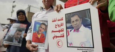 Paramedics from the Palestine Red Crescent Society, PRCS, one carrying a poster that reads "I was saving lives but they killed me," hold signs to honor members of medical missions who lost their lives while carrying out their humanitarian duty, in front of their headquarters in the West Bank city of Ramallah, Wednesday, April 23, 2025. (AP Photo/Nasser Nasser)