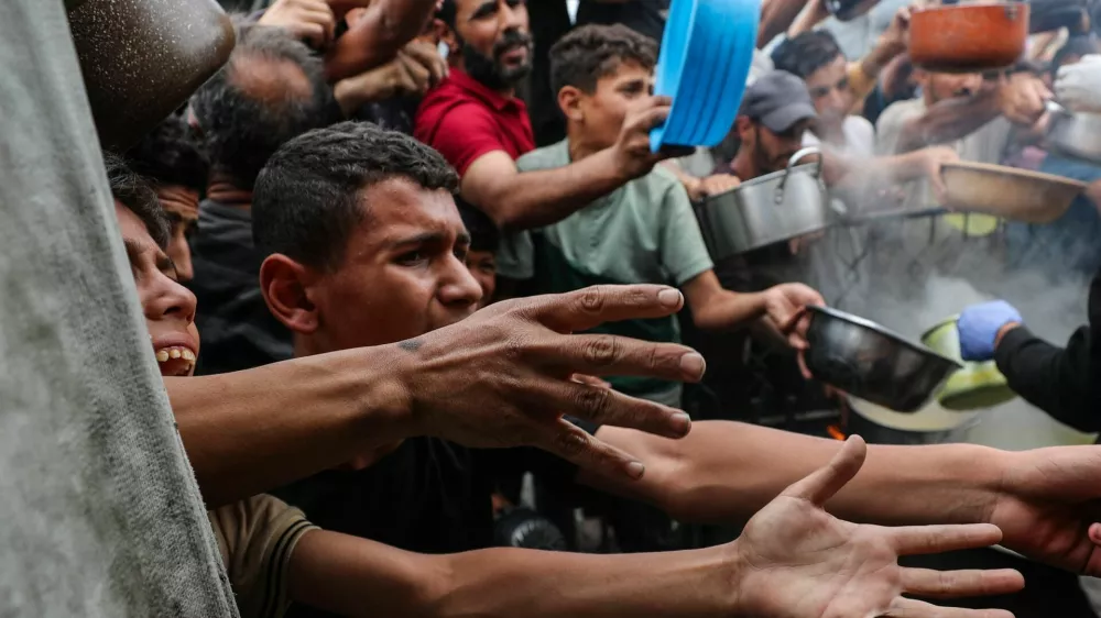 Palestinians wait to receive food cooked by a charity kitchen, in Beit Lahia, northern Gaza Strip, April 24, 2025. REUTERS/Mahmoud Issa