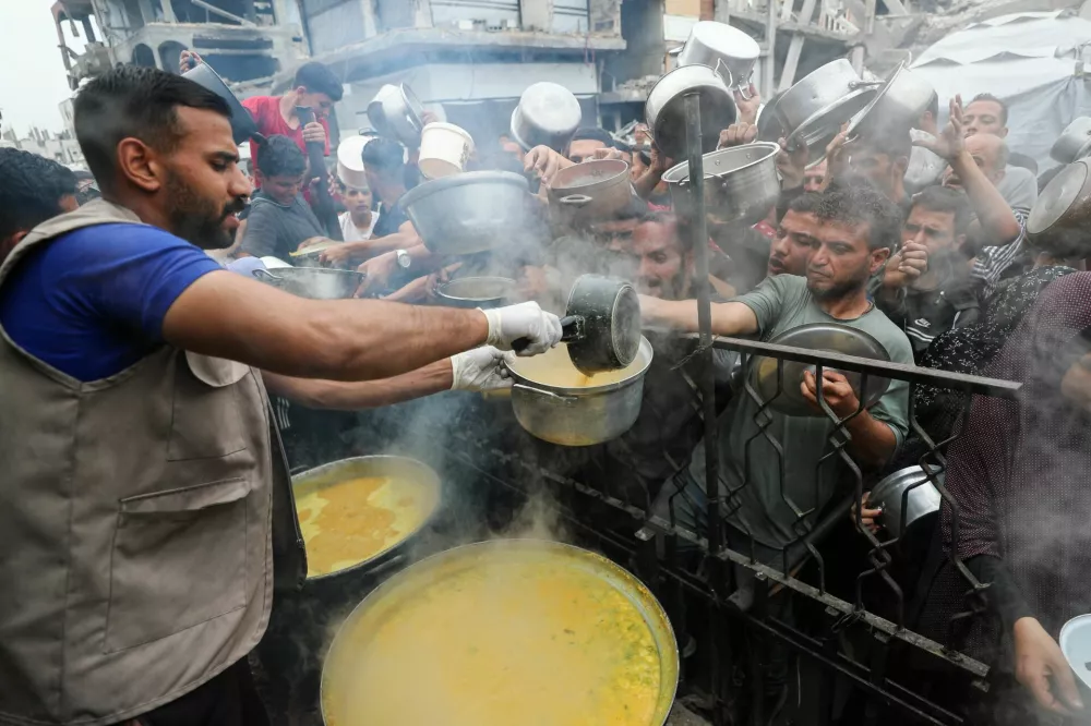 Palestinians receive food cooked by a charity kitchen, in Beit Lahia, northern Gaza Strip, April 24, 2025. REUTERS/Mahmoud Issa