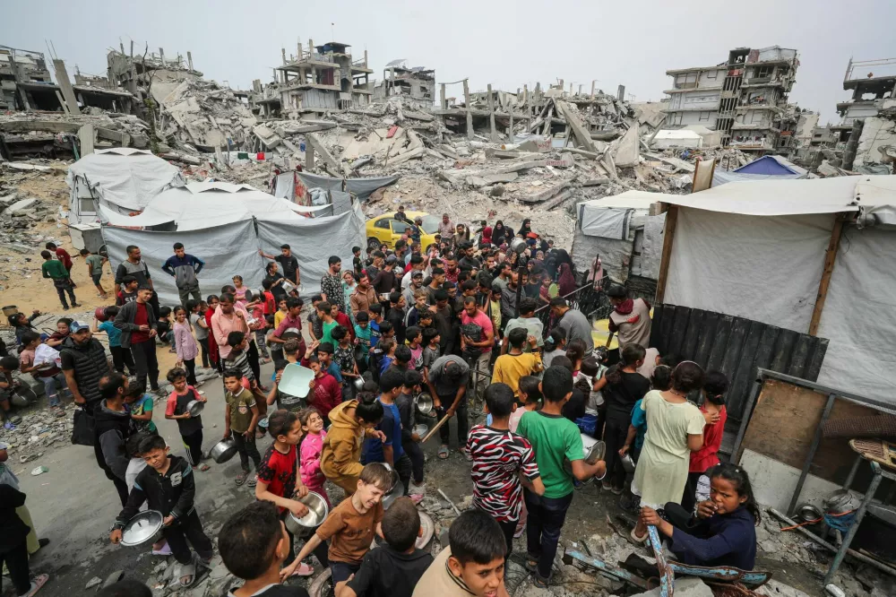 Palestinians wait to receive food cooked by a charity kitchen, in Beit Lahia, northern Gaza Strip, April 24, 2025. REUTERS/Mahmoud Issa