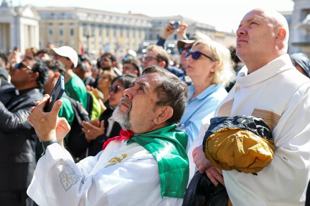 Faithful watch as the coffin of Pope Francis arrives on the day of the funeral Mass in St. Peter's Square, at the Vatican, April 26, 2025. REUTERS/Kevin Coombs