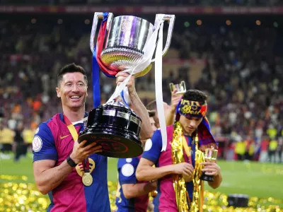 Barcelona's Robert Lewandowski lifts the trophy after winning the Spanish Copa del Rey final soccer match between Barcelona and Real Madrid at Estadio de La Cartuja stadium in Seville, Spain, Sunday, April 27, 2025. (AP Photo/Jose Breton)