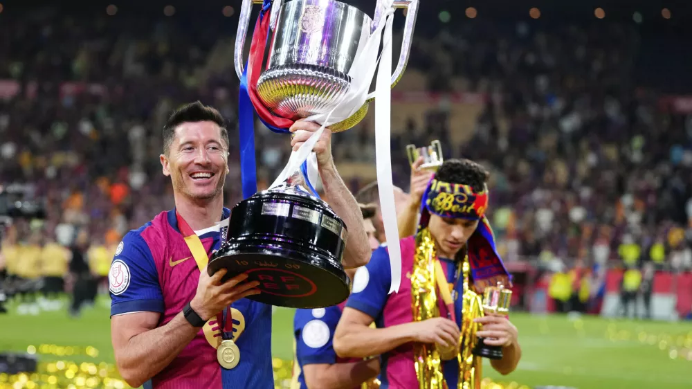 Barcelona's Robert Lewandowski lifts the trophy after winning the Spanish Copa del Rey final soccer match between Barcelona and Real Madrid at Estadio de La Cartuja stadium in Seville, Spain, Sunday, April 27, 2025. (AP Photo/Jose Breton)