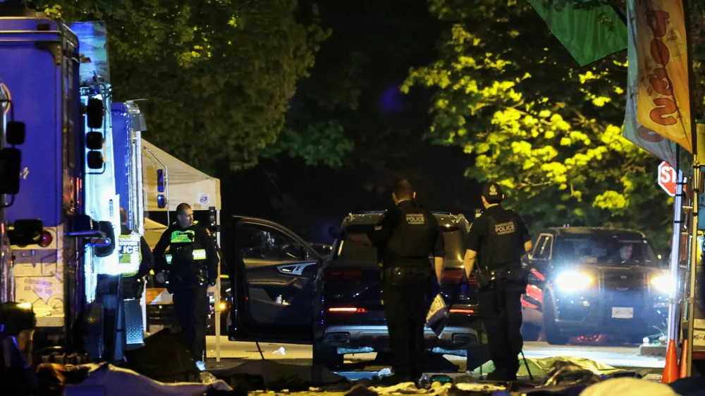 Police officers work by a SUV, which was driven into a crowd at the Lapu Lapu day block party, as bodies of victims lie covered on the ground, in Vancouver, Canada April 27, 2025. REUTERS/Chris Helgren