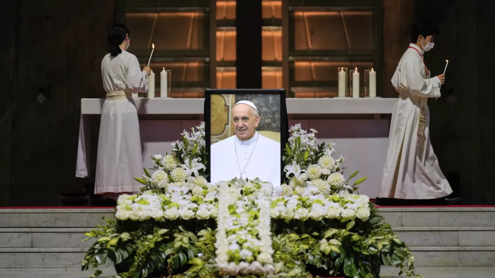 Priests prepare for a memorial Mass for the late Pope Francis near his portrait at St. Mary's Cathedral in Tokyo, Sunday, April 27, 2025. (AP Photo/Hiro Komae, Pool)