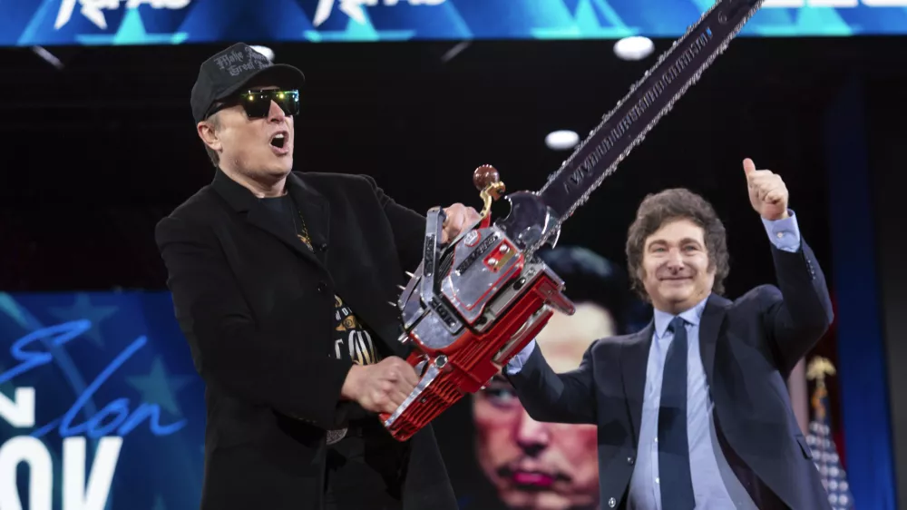 Elon Musk holds up a chainsaw he received from Argentina's President Javier Milei, right, as they arrive to speak at the Conservative Political Action Conference, CPAC, at the Gaylord National Resort & Convention Center, Thursday, Feb. 20, 2025, in Oxon Hill, Md. (AP Photo/Jose Luis Magana)