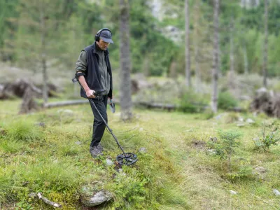 Man on a treasure hunt with a recreational metal detector, shovel and headphones. Electronic treasure finder. Blurred background and copy space / Foto: Alemasche72