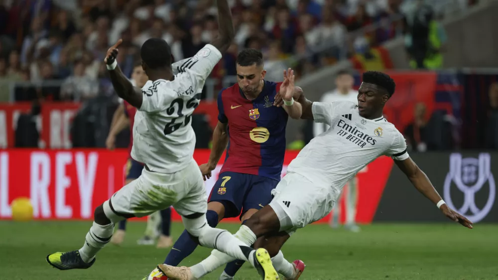 Barcelona's Ferran Torres, center, is challenged by Real Madrid's Antonio Rudiger, left, and Real Madrid's Aurelien Tchouameni during the Spanish Copa del Rey final soccer match between Barcelona and Real Madrid at Estadio de La Cartuja stadium in Seville, Spain, Saturday, April 26, 2025. (AP Photo/Joan Monfort)
