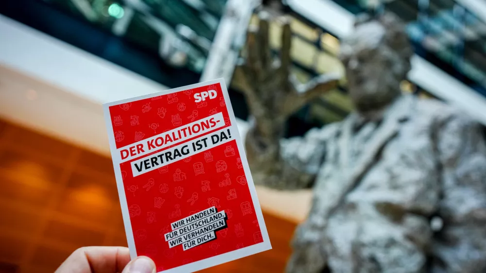 30 April 2025, Berlin: An advertising card with the inscription "The coalition agreement is here" can be seen at the Social Democratic Party of Germany (SPD) party headquarters, the Willy Brandt House, in front of the Willy Brandt statue. SPD has approved a coalition agreement with Friedrich Merz's conservative bloc in a members' ballot, paving the way for the new German government to take office next week. Photo: Kay Nietfeld/dpa