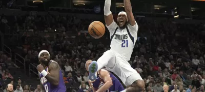 Dallas Mavericks center Daniel Gafford dunks over Phoenix Suns forward Ryan Dunn (0) and center Mason Plumlee during the second half of an NBA basketball game, Friday, Dec. 27, 2024, in Phoenix. Dallas won 98-89. (AP Photo/Rick Scuteri)