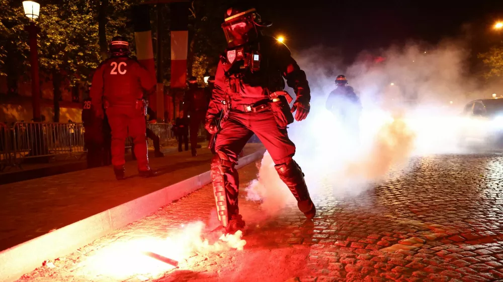Soccer Football - Champions League - Fans celebrate after Paris St Germain qualifies for the final - Paris, France - May 7, 2025 A police officer puts out a flare during the Paris St Germain fans celebration after reaching the final near the Champs Elysees avenue REUTERS/Abdul Saboor
