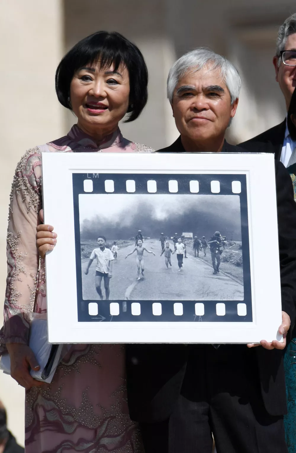 Pulitzer Prize-winning photographer Nick Ut (R), flanked by Kim Phuc, known as the 'Napalm Girl', shows his 1972 Vietnam war iconic photo as they wait to meet Pope Francis at the end of the weekly general audience in St. Peter s Square, Vatican on May 11, 2022.