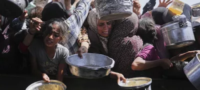 Palestinians struggle to get donated food at a community kitchen in Khan Younis, Gaza Strip, Friday, May 16, 2025. (AP Photo/Abdel Kareem Hana)