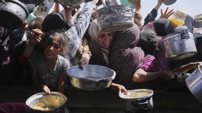 Palestinians struggle to get donated food at a community kitchen in Khan Younis, Gaza Strip, Friday, May 16, 2025. (AP Photo/Abdel Kareem Hana)