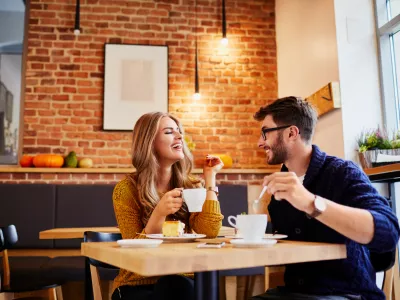 Couple of young people drinking coffee and eating cake in a stylish modern cafeteria