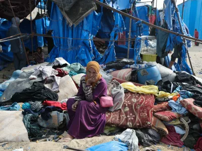 A Palestinian woman sits at the site of an Israeli airstrike on a tent sheltering displaced people, in Deir Al-Balah in the central Gaza Strip, May 17, 2025. REUTERS/Ramadan Abed
