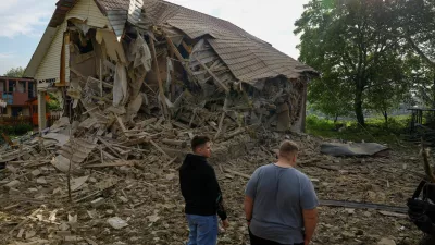 Resident Vadym Tsybenko, 22-year-old, and his relative stands next a house of his neighbours, heavily damaged by a Russian drone strike, amid Russia's attack on Ukraine, outside of Kyiv, Ukraine May 18, 2025. REUTERS/Valentyn Ogirenko