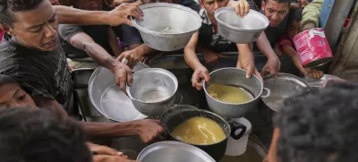 Palestinians struggle to receive cooked food distributed at a community kitchen in Khan Younis, southern Gaza Strip, Wednesday, May 14, 2025. (AP Photo/Abdel Kareem Hana)