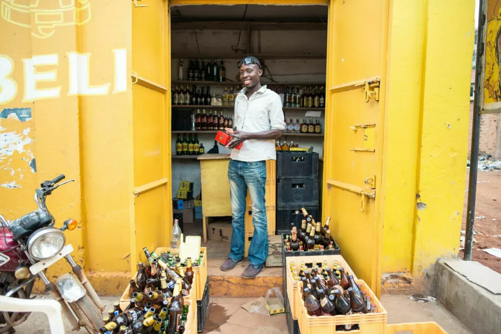 Jinja / Uganda - September 15, 2016: African man smiles in front of alcoholic drinks store / Foto: Juan Alberto Casado