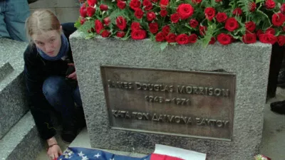 A fan of the Doors' lead singer Jim Morrison lays out an American flag with the likeness of the rock poet at his gravesite in Pere Lachaise Cemetery in Paris Wednesday July 3,1996 the day of the 25th anniversary of the rock singer's death. Many fans from Europe, the United States and Japan bearing candles gathered to pay homage to the dead rock star who has gained a cult status. (AP Photo/Michel Lipchitz)
