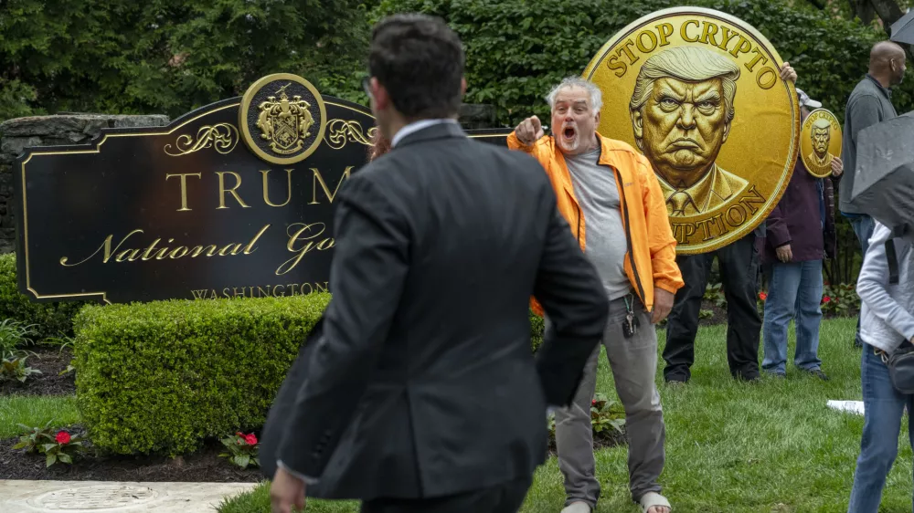 IMAGE DISTRIBUTED FOR OUR REVOLUTION - An activist calls out an attendee of an exclusive dinner at Trump National Golf Course as he and fellow activist from Our Revolution protest influence-peddling & corruption, Thursday, May 22, 2025 in Sterling, Va. Inside, the top 220 holders of the President's cryptocurrency have paid over $394 million for spots at an exclusive dinner with Trump. (Kevin Wolf/AP Content Services for Our Revolution)
