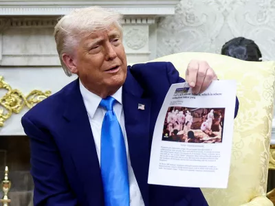 FILE PHOTO: U.S. President Donald Trump shows a copy of an article that he said is about white South Africans who had been killed, in the Oval Office of the White House in Washington, D.C., U.S., May 21, 2025. REUTERS/Kevin Lamarque/File Photo