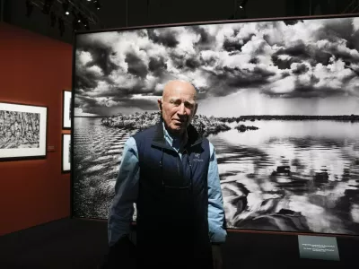 FILE - Brazilian photographer Sebastiao Salgado poses in front of one of the pictures of his 'Amazonia' exhibition in Milan, Italy, May 11, 2023. Salgado, known for his long-term projects and images of nature and humanity, died at age 81, the Instituto Terra confirmed on Friday, May 23, 2025.. (AP Photo/Luca Bruno, File)