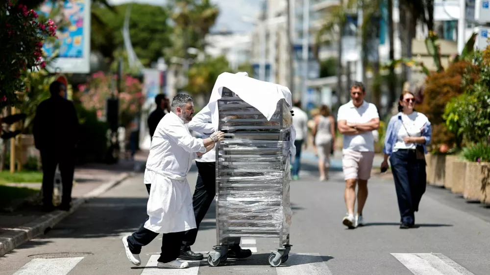 Cooks bring out the food from the Carlton Hotel Beach Club on the Croisette following a major electricity outage, during the 78th Cannes Film Festival in Cannes, May 24, 2025. REUTERS/Benoit Tessier