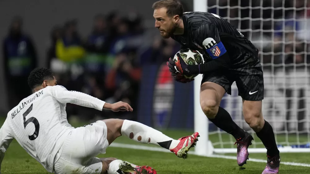 Atletico Madrid's goalkeeper Jan Oblak saves in front of Real Madrid's Jude Bellingham during the Champions League round of 16, second leg, soccer match between Atletico Madrid and Real Madrid at the Metropolitano stadium in Madrid, Spain, Wednesday, March 12, 2025. (AP Photo/Bernat Armangue)