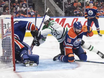 Dallas Stars' Mason Marchment (27) and Edmonton Oilers' Jake Walman (96) battle as Oilers goalie Stuart Skinner, left, makes a save during the third period of Game 3 of the NHL hockey Stanley Cup Western Conference finals in Edmonton, Alberta, Sunday, May 25, 2025. (Jason Franson/The Canadian Press via AP)