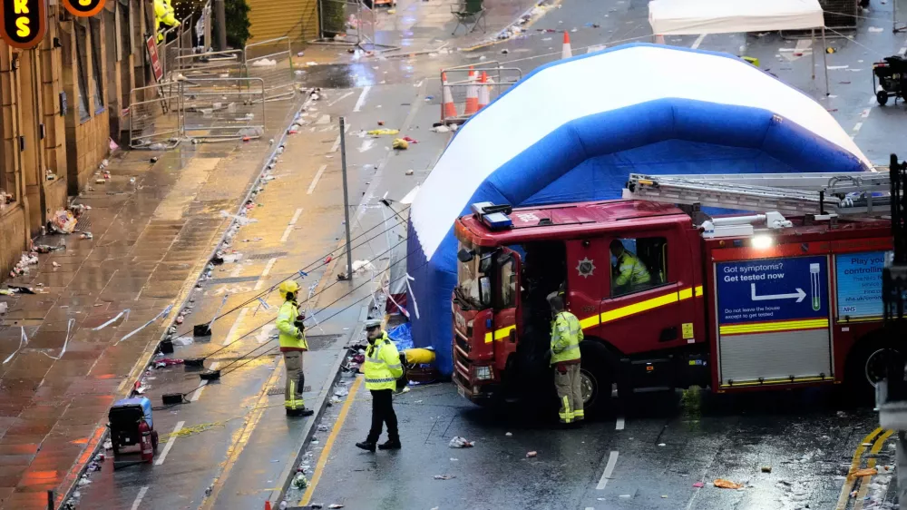 Police and emergency personnel walk next to a tent at the site of an incident on Water Street near the Liver Building in Liverpool after a car collided with pedestrians during the Premier League winners parade, in Liverpool, England, Monday May 26, 2025. (Danny Lawson/PA via AP)