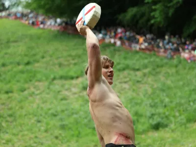 Tom Kopke, from Munich, holds a cheese wheel after winning the first race of the annual Cooper's Hill Cheese-Rolling and Wake competition near Brockworth, Britain, May 26, 2025. REUTERS/Isabel Infantes