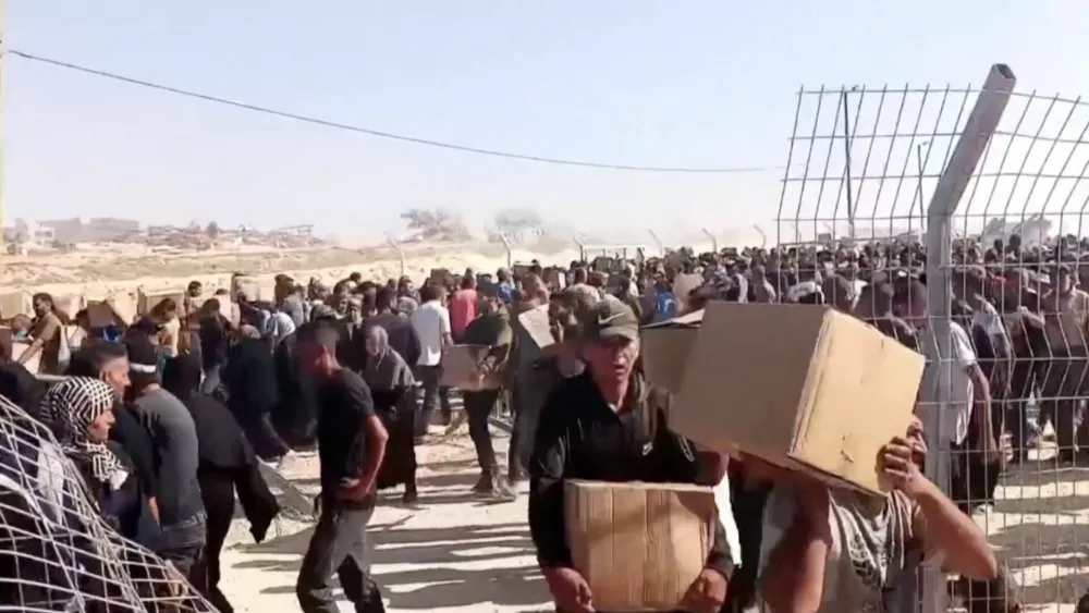 Palestinians walk back carrying aid boxes, in Rafah, in the southern Gaza Strip, May 27, 2025, in this screengrab from a video. Reuters TV/via REUTERS