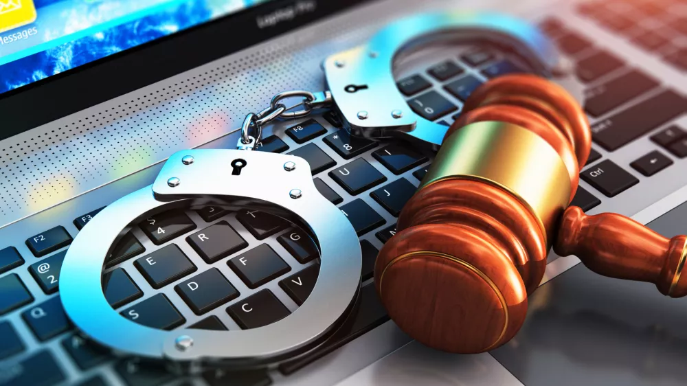 Creative abstract cyber crime, online piracy and internet web hacking concept: 3D render illustration of the macro view of metal handcuffs and wooden judge mallet, gavel or hammer on laptop notebook computer keyboard with selective focus effect / Foto: Scanrail