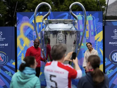 People take pictures at a giant trophy during the opening of the official UEFA fan festival in Munich, Germany, Thursday, May 29, 2025 ahead of the Champions League final soccer match between Inter and PSG. (AP Photo/Matthias Schrader)