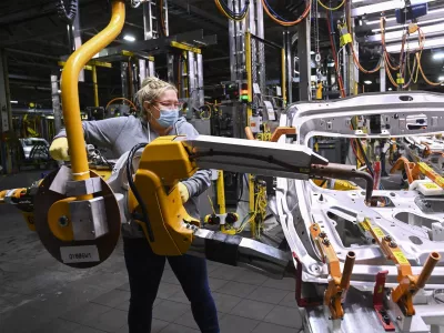 FILE - GM workers use human assistance automation to weld vehicle doors at the General Motors assembly plant during the COVID-19 pandemic in Oshawa, Ontario, March 19, 2021. (Nathan Denette/The Canadian Press via AP, File)
