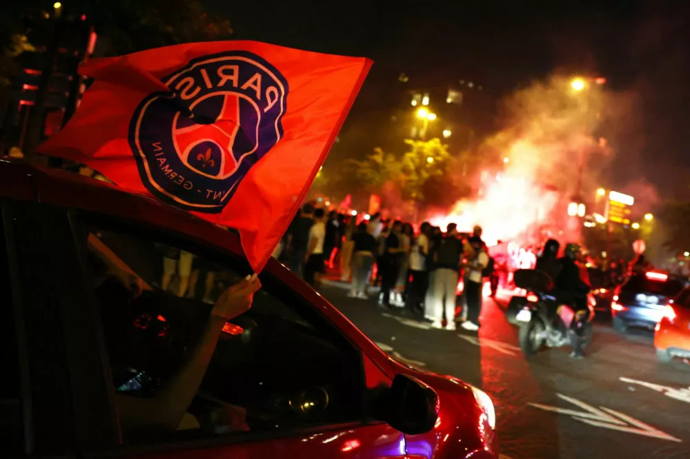 Soccer Football - Champions League - Final - Paris St Germain fans gather in Paris - Paris, France - May 31, 2025 Paris St Germain fans wave a flag out of a car window after winning the Champions League REUTERS/Tom Nicholson
